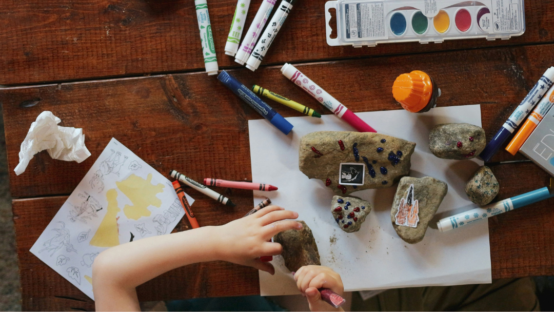 A child painting rocks with pens and paint at a community playgroup