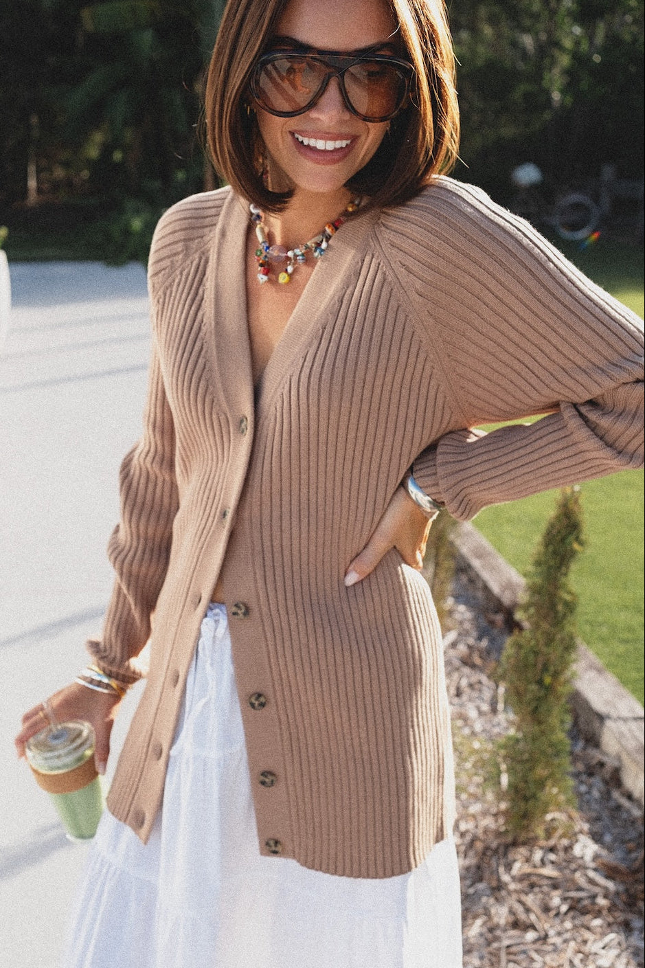 Woman wearing a beige cardigan and sunglasses outdoors